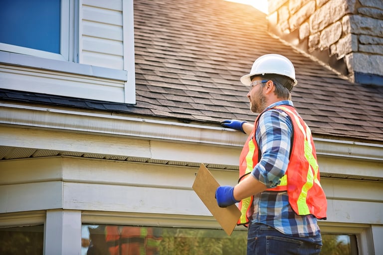 Man with hard hat inspecting house roof